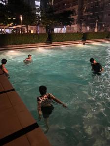 eine Gruppe von Männern in einem Schwimmbad in der Nacht in der Unterkunft MISR Suite QC in Manila