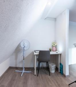 Cette chambre comprend un bureau avec un ventilateur et une chaise. dans l'établissement #2 Großes Zimmer mit Pool und Garten, à Memmingen