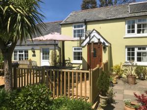 a yellow house with a wooden fence in front of it at Bumble Bee Cottage in Hartland