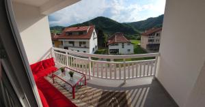 a balcony with a red couch and a view of a mountain at Rooms Mery in Visoko