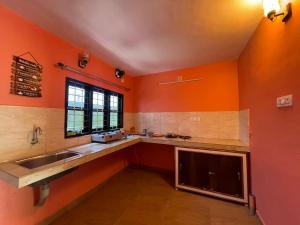 a kitchen with orange walls and a sink and a window at Mountain cheers munnar in Munnar