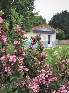 una pequeña casa con flores rosas delante en Chambre d'hôtes de l'Ancienne école, en RiviÃ¨res