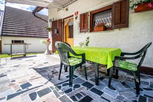 a green table and chairs on a patio at Holiday house Lepena in Soča
