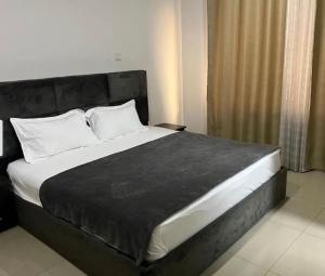1 dormitorio con 1 cama grande con almohadas blancas en JaneChill Guest House, en Accra