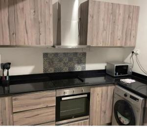 a kitchen with wooden cabinets and a stove and a microwave at JaneChill Guest House in Accra