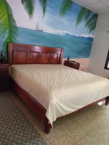 um quarto com uma cama com uma pintura de uma praia em Casa Hotel Familiar 