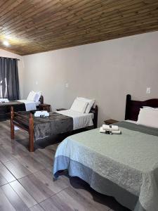 a bedroom with two beds and a wooden ceiling at Pousada Recanto dos Canyons in Praia Grande