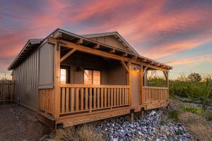 a cabin with a wrap around porch with a sunset at Miners Cabin #2 - One Queen Bed - Accessible Room - Private Balcony in Tombstone