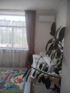 a bedroom with a bed and a plant in front of a window at Таунхаус in Bishkek