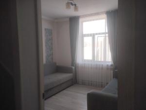 a living room with a couch and a window at Таунхаус in Bishkek