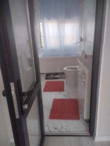 a bathroom with a toilet and two red rugs at Таунхаус in Bishkek