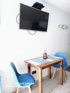 a dining room table with a tv and blue chairs at Apartamenty u Rybaka in Jastarnia