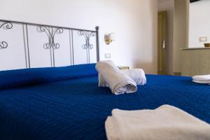 a bedroom with a blue bed with towels on it at Hotel Villa Senator Mediterraneo in Tortora