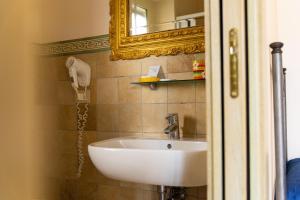 un lavandino bianco in un bagno con specchio di Hotel Villa Senator Mediterraneo a Tortora