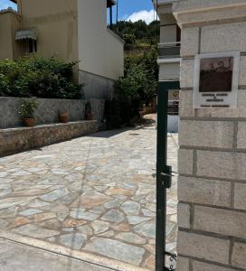 a sign on the side of a building next to a stone sidewalk at Dionysus Sivota Center in Sivota