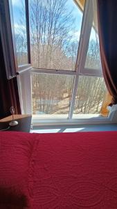 a bedroom with a red bed and a large window at Appartement Le Montagnard in Les Déserts