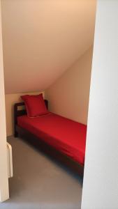 Appartement Le Montagnard في Les Déserts: سرير احمر ومخدة حمراء في الغرفة