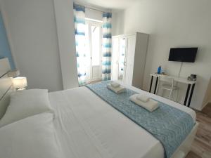 Un dormitorio con una gran cama blanca con dos toallas encima. en Iris Rooms, en Cagliari