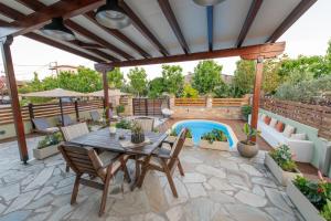 un patio con mesa, sillas y piscina en Villa Fylira, en Kato Gatzea