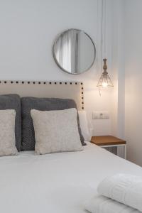 1 dormitorio con cama blanca y espejo en tuGuest Gran Vía Apartments, en Granada