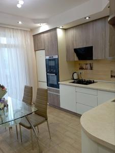 eine Küche mit einem Glastisch mit Stühlen und einer Theke in der Unterkunft Apartment - Dzhordzha Vashynhtona in Lwiw
