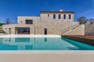 a stone house with a swimming pool in front of it at Agriturismo Colli Martani in Massa Martana