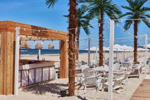 a table and chairs on a beach with palm trees at Penthouse C51 - Golden Tulip in Międzyzdroje