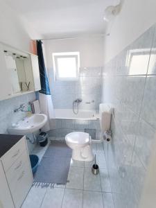 La salle de bains blanche est pourvue de toilettes et d'un lavabo. dans l'établissement Apartmani Biba, à Novi Vinodolski