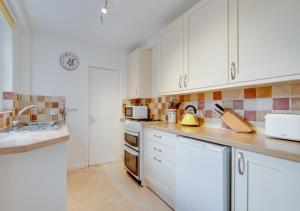 een keuken met witte kasten en een wastafel bij Glenisla in Sidmouth