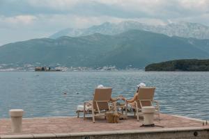 two people sitting around a table on the edge of a body of water at Villa Gioia in Tivat