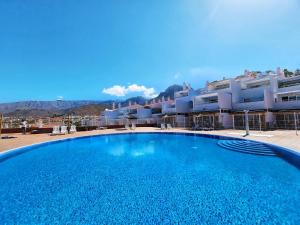 a large blue swimming pool in front of a building at Ocean View Villas Canarias in Adeje