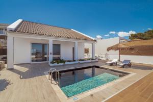 una villa con piscina di fronte a una casa di Luxury Villa Cavo Mare Thalassa with private pool & jacuzzi a Plános