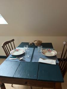 una mesa azul con platos y vasos. en La vigie d'Héloïse, appartement de l'Aod en Lampaul