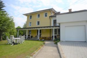 une grande maison jaune avec un garage blanc dans l'établissement Pension Eule, à Sankt Kanzian