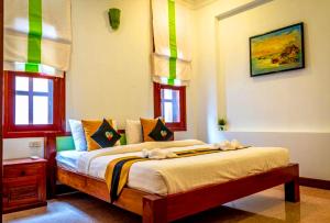 a bedroom with a bed in a room with windows at Antonios Villa Hotel in Siem Reap