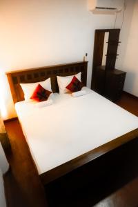 ein Schlafzimmer mit einem großen weißen Bett mit roten Kissen in der Unterkunft White Win Villa in Elewala