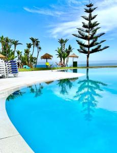 een zwembad in een resort met een boom in het water bij Summer House duplex en la playa con piscina in Benalmádena