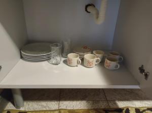 una mesa blanca con tazas y platos. en Flats Brancas Nuvens en Campos do Jordão