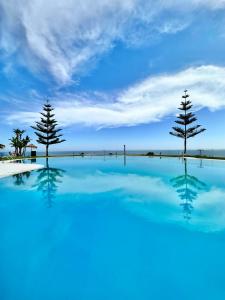 twee bomen in een zwembad met een blauwe lucht bij Summer House duplex en la playa con piscina in Benalmádena