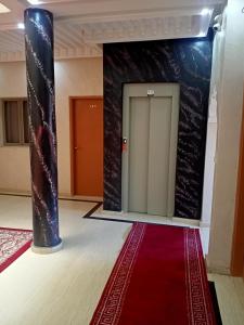 um quarto amplo com um tapete vermelho e uma porta em Hotel Tidinit em Guelmim