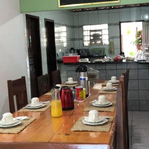 una larga mesa de madera con platos y jarras de zumo de naranja en Pousada Palmeiras en Santo Amaro