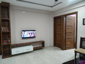 sala de estar con TV en la pared en Manasvi en Mangalore