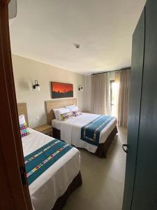 a hotel room with two beds and a window at Eco Resort QUINTA SANTA BÁRBARA in Pirenópolis