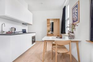 a kitchen with a white table and chairs in a room at Sleepcph in Copenhagen