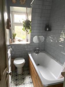 a bathroom with a white tub and a toilet at Bright Cosy 1 Bed Apartment, SE London in Chislehurst