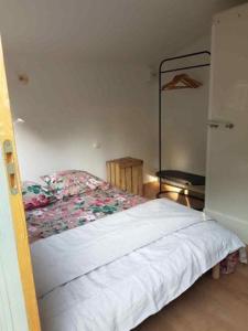 a bedroom with a white bed with flowers on it at La cabane de Mimi la Sardine in Saint-Gervais en-Belin