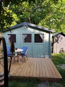 a blue shed with a table on a deck at La cabane de Mimi la Sardine in Laigné-en-Belin