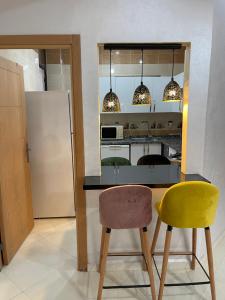 a kitchen with two chairs and a counter and a refrigerator at Moderne appartement meublé (avec Wifi) in Fès