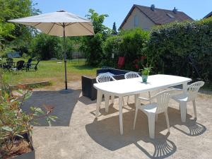 una mesa blanca y sillas con sombrilla en L'échappée Comtoise, en Baume-les-Dames