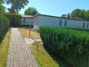 a brick path next to a building and a hedge at Doppelbungalow Ostsee Nr. 8 + 9 in Ahlbeck